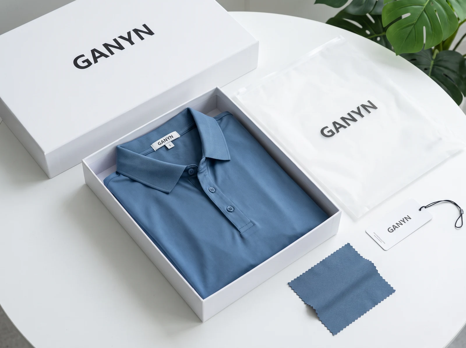 Folded golf polo inside a correctly sized branded apparel box with printed garment bag