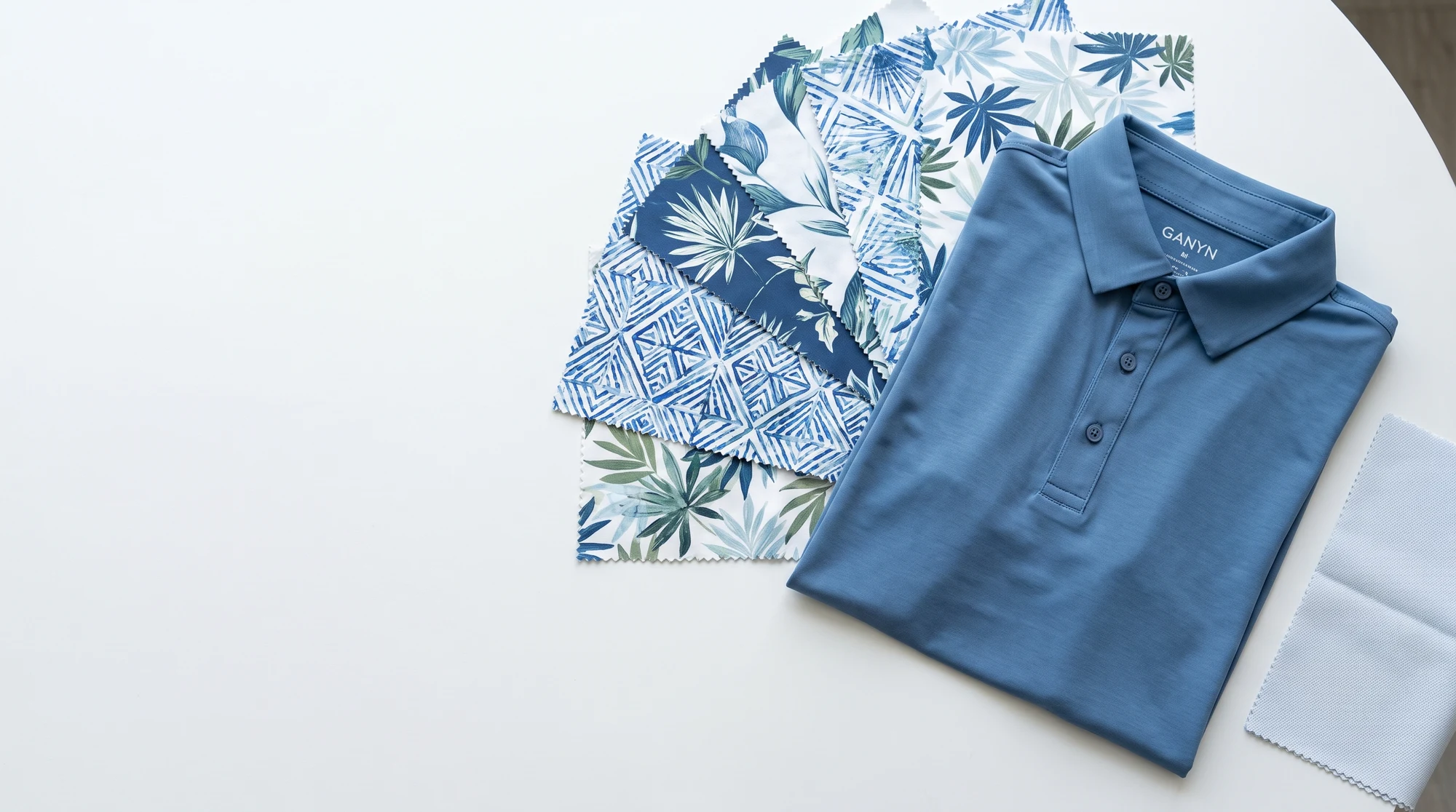 Golf apparel print strike-offs and a navy polo on a development table