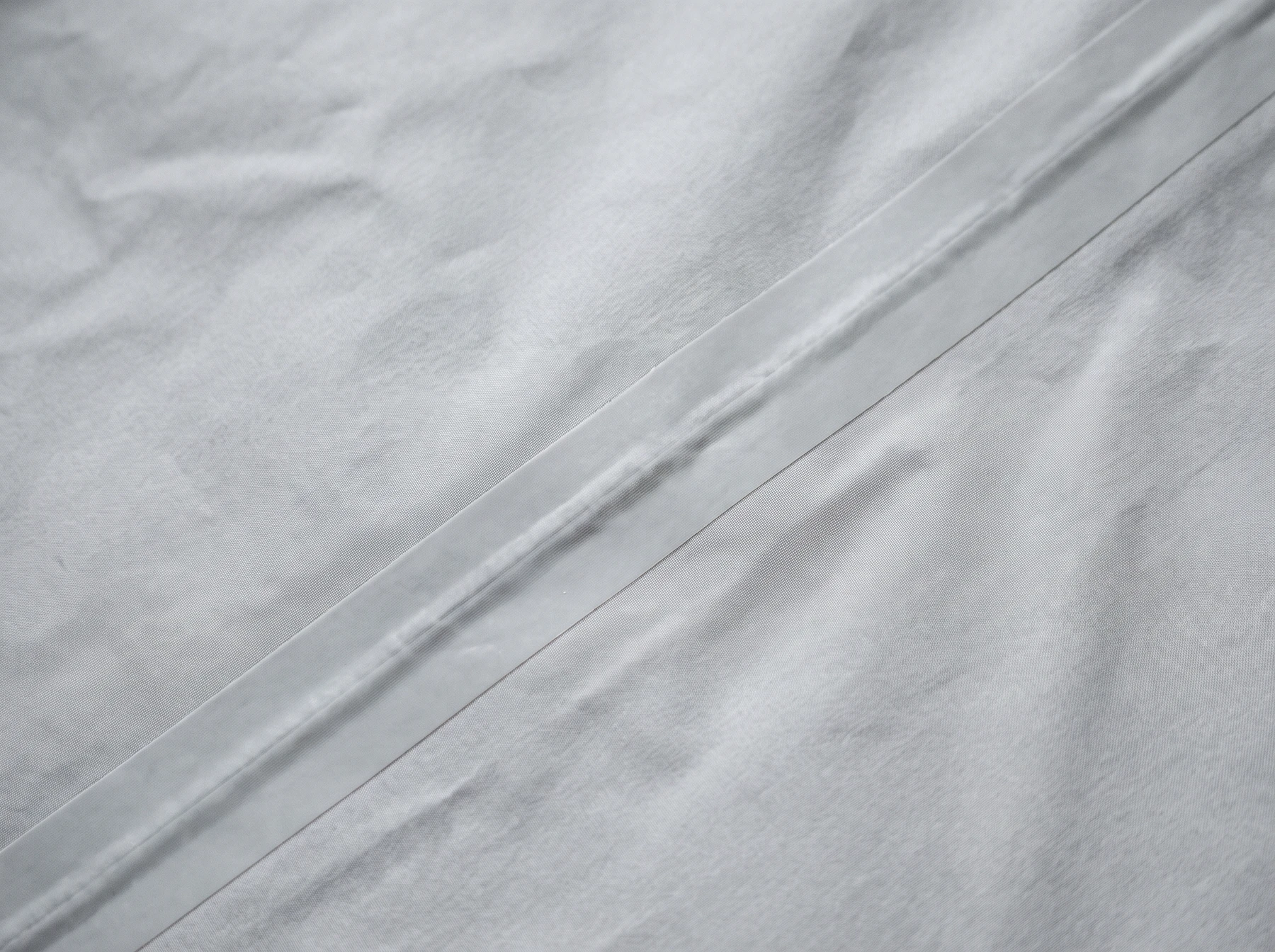Thin laminated golf rain-shell interior with smooth heat-bonded seam tape and no stitches through the tape